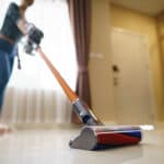 Vacuum head in the foreground as Airbnb cleaner vacuums floor
