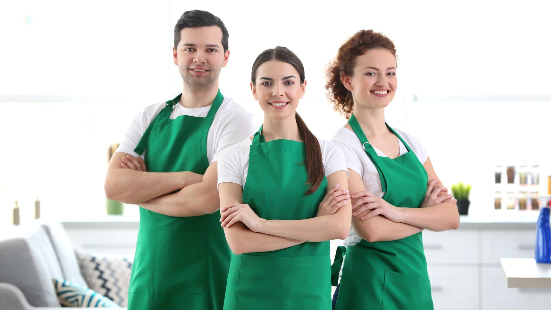 Three cleaners standing together with their arms crossed and smiling