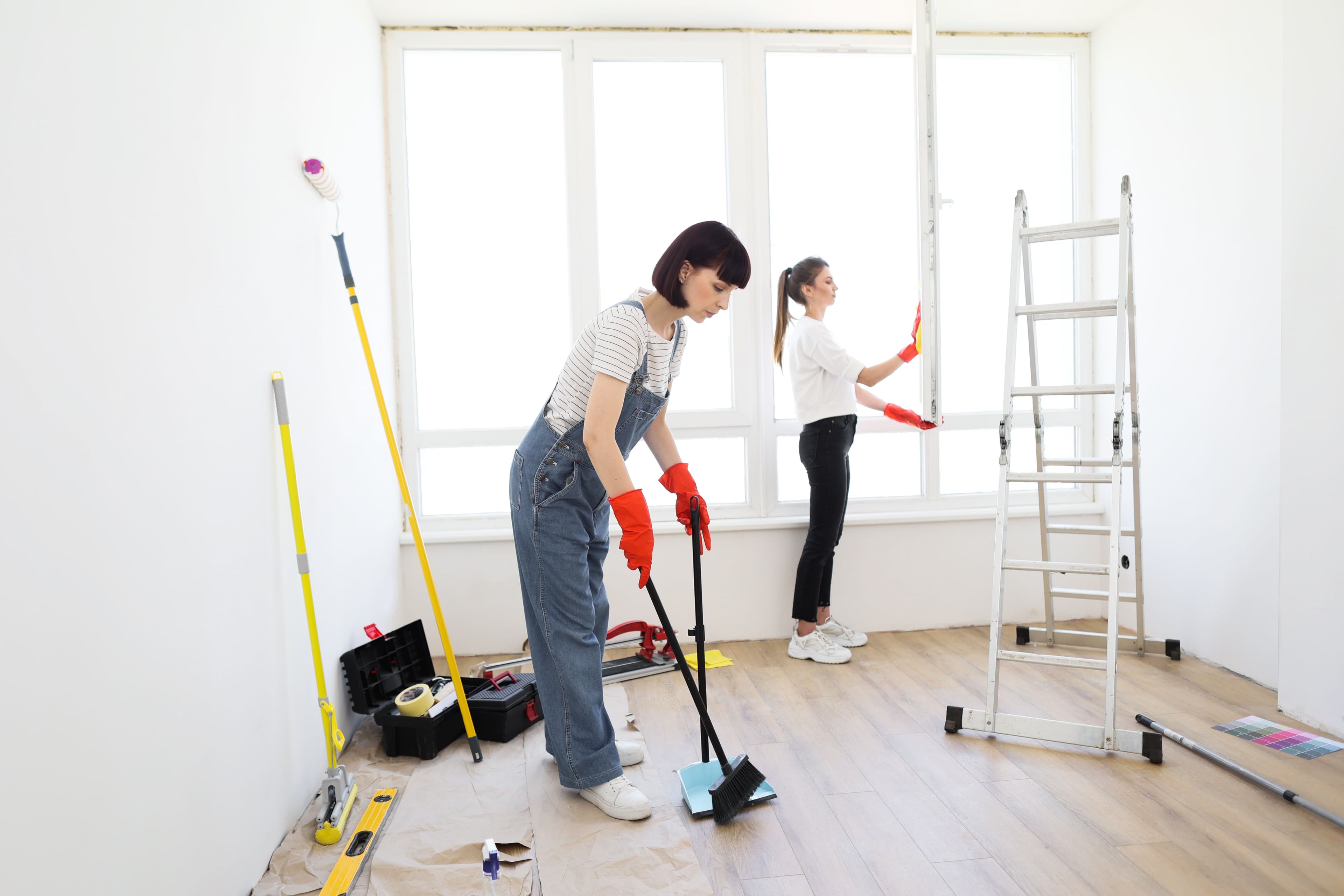 Two move out cleaning service crew members cleaning an empty bedroom