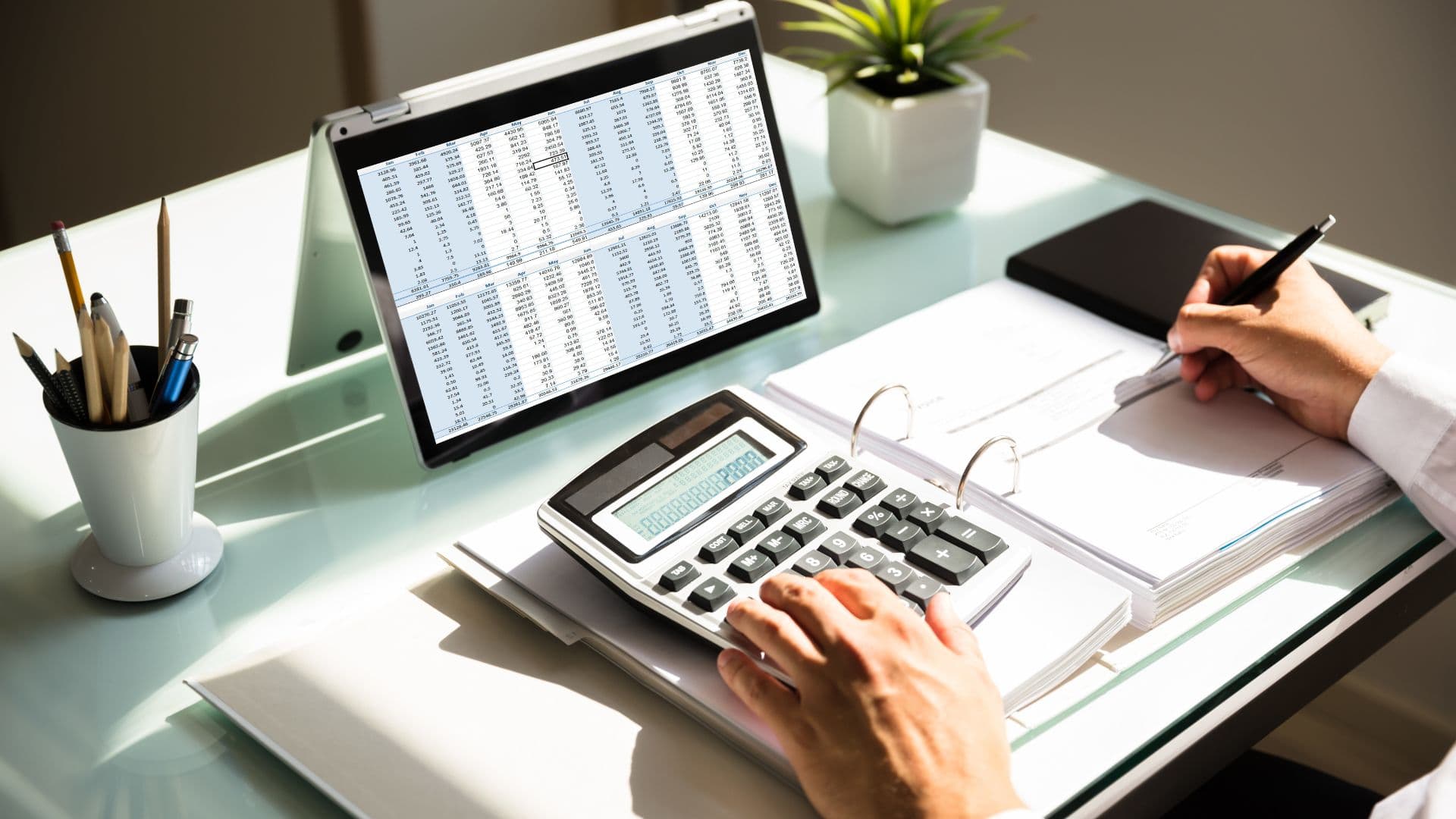 Hands pushing buttons on a calculator while looking at field service invoices