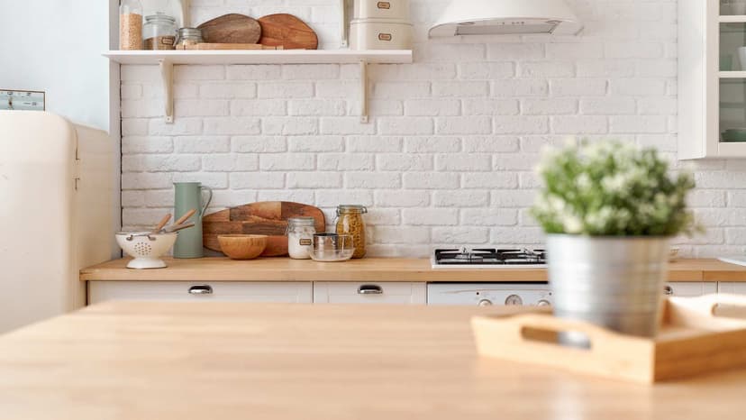 Kitchen counter with a potted plant to the right and kitchen supplies in the background