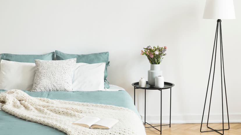 Airbnb bedroom with a lamp and vase of flowers next to bed