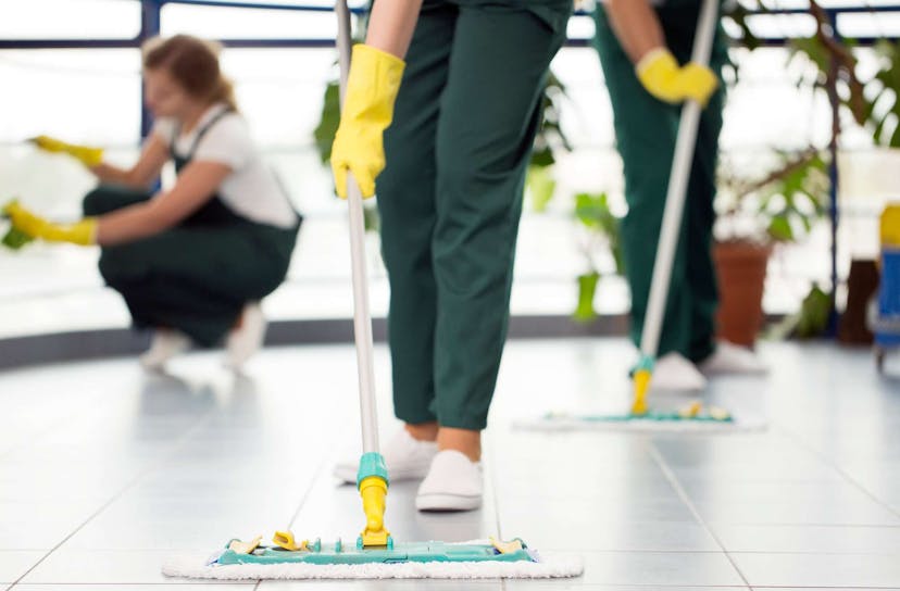 Cleaning crew with gloves on dusting the floor with mop dusters