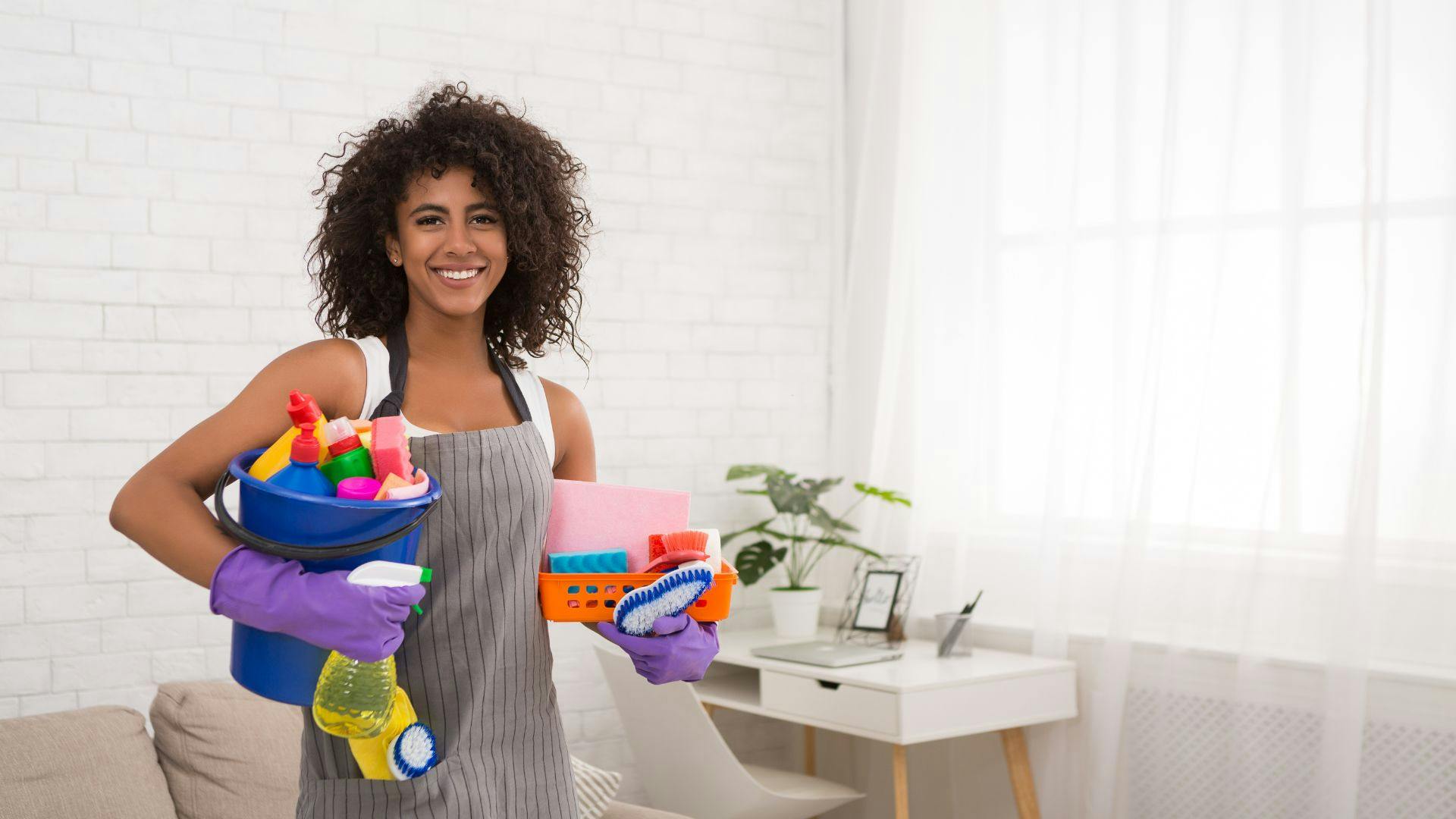 Field service cleaner holding cleaning supplies in her hands as she smiles