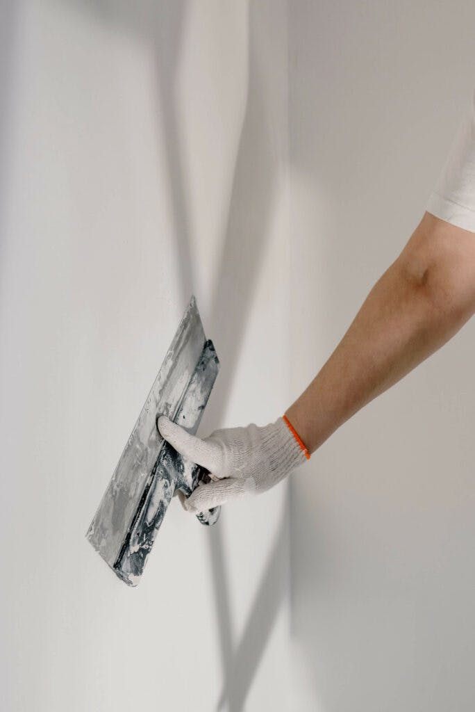 Gloved hand smoothing out wall paste