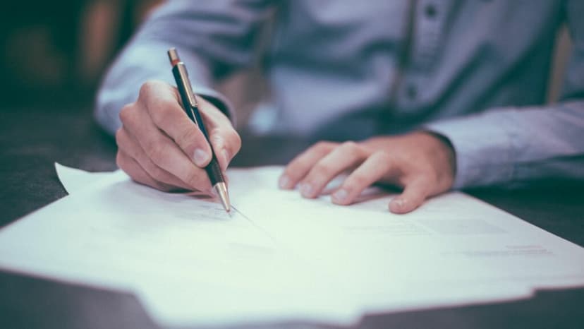 Man in a button down writing on a sheet of paper with a pen