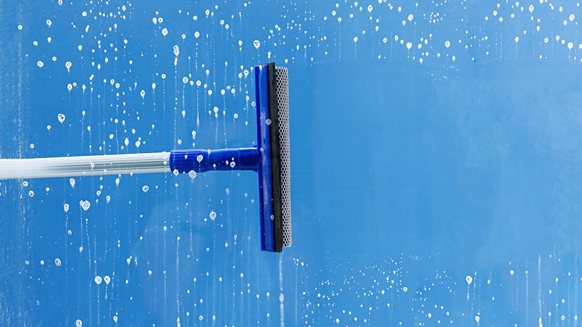 Window cleaning service squeegee pulling away soap suds 