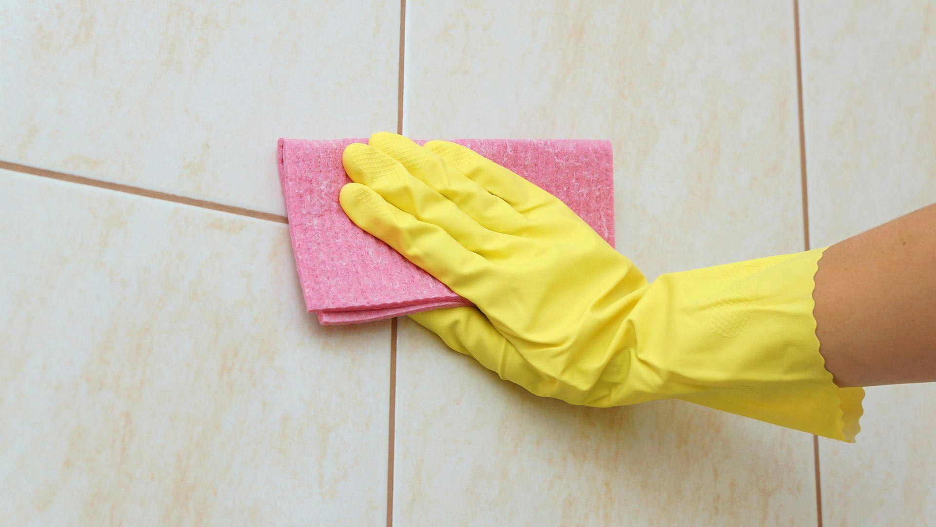 Gloved hand cleaning tile