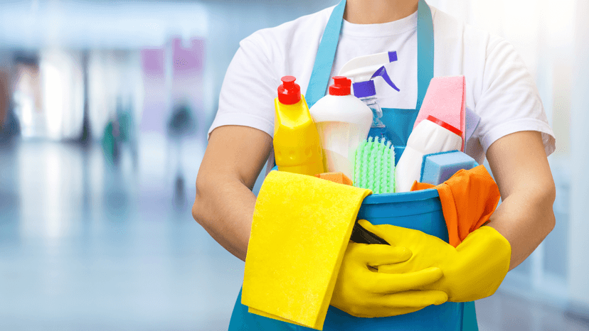 Cleaner holding a bucket with different cleaning supplies