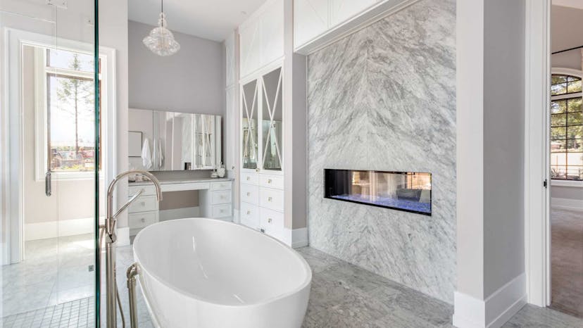 Marble walled bathroom with white tub in the middle