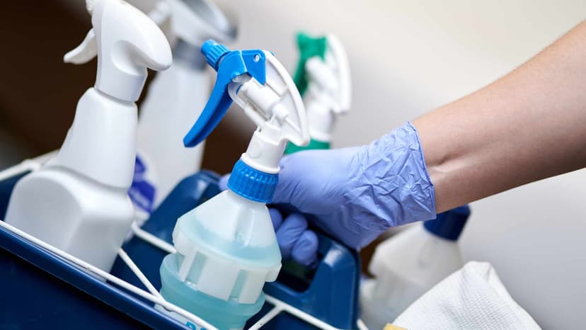 Cleaner holding a cleaning caddy with a gloved hand