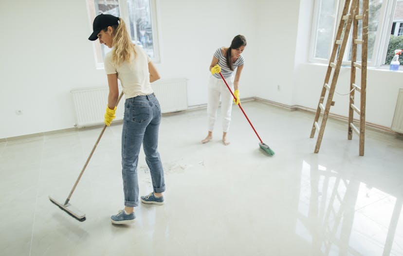 two women sweeping an empty living room for a move out cleaning service