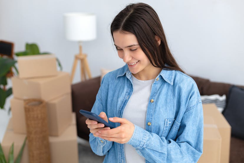 Woman on her phone with moving boxes behind her