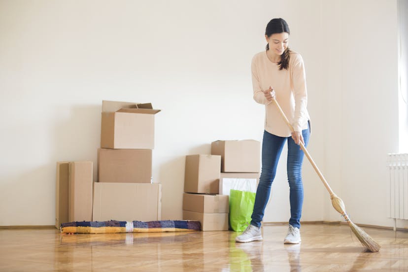 Woman sweeping floor with moving boxes in the background
