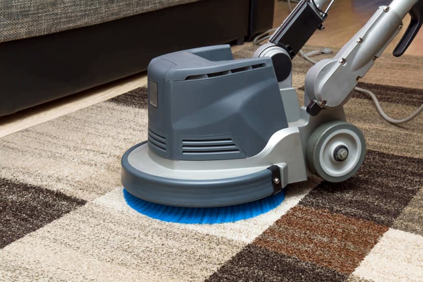 Carpet cleaner equipment on brown checkered rug in a large room.