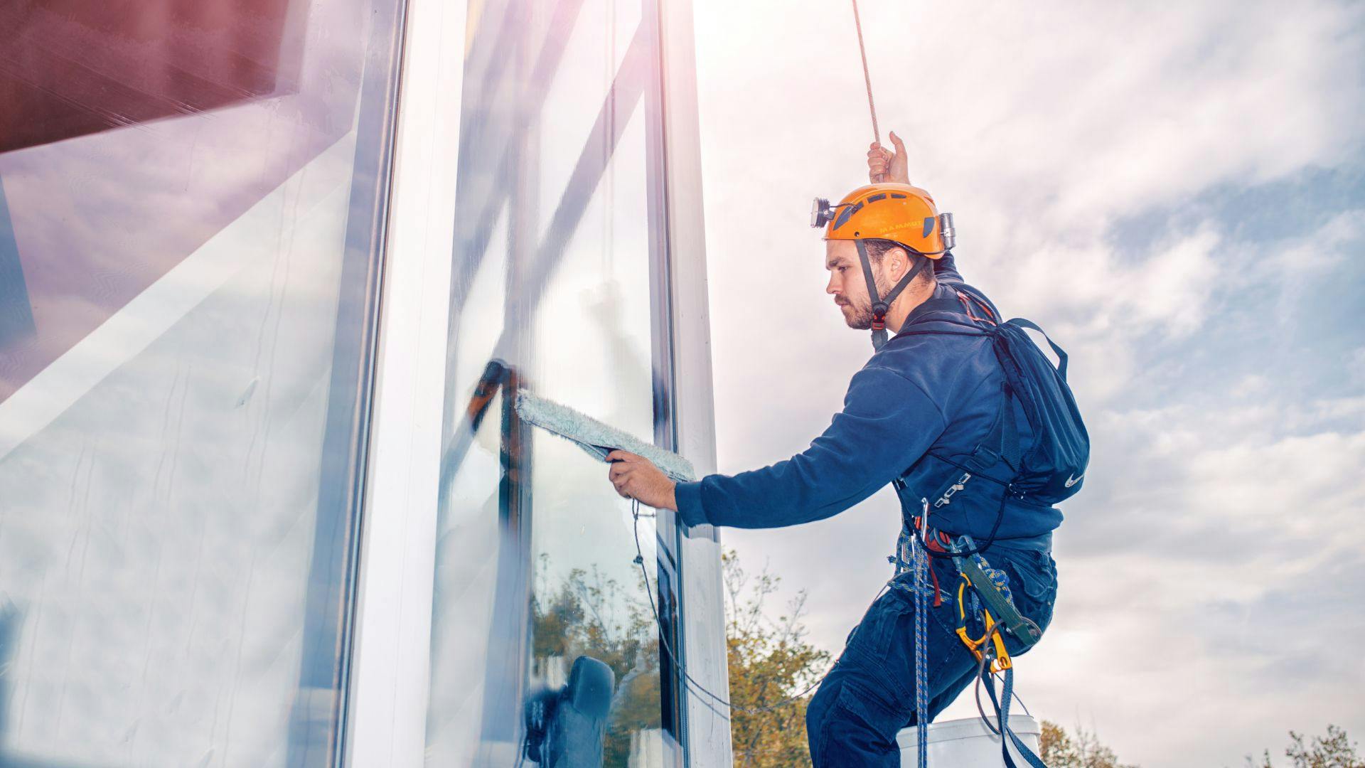 Professional window washer cleaning windows in a harness